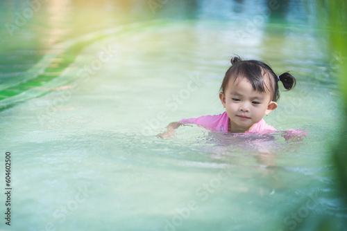 Girl wearing a swim suit splashing in the swimming pool.