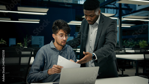 Wallpaper Mural Male African boss businessman mentor teaching indian man trainee new employee discuss online business project on laptop explain details documents to colleague men working together teamwork in office Torontodigital.ca