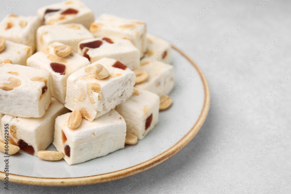 Pieces of delicious nutty nougat on light table, closeup