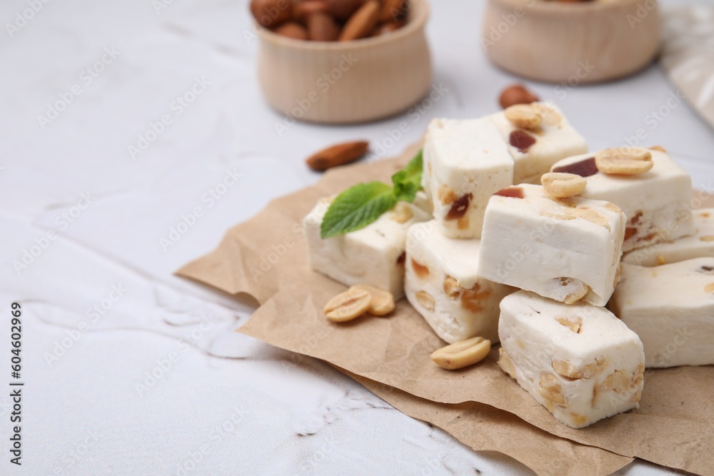 Pieces of delicious nutty nougat on parchment paper, closeup. Space for text