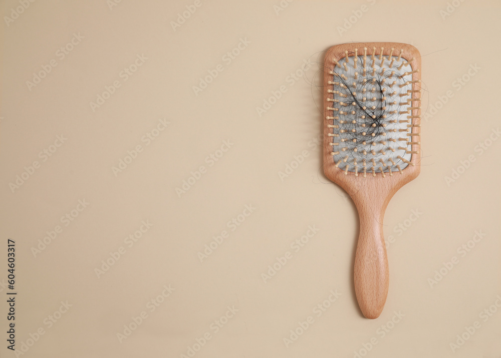 Fototapeta premium Wooden brush with lost hair on beige background, top view. Space for text