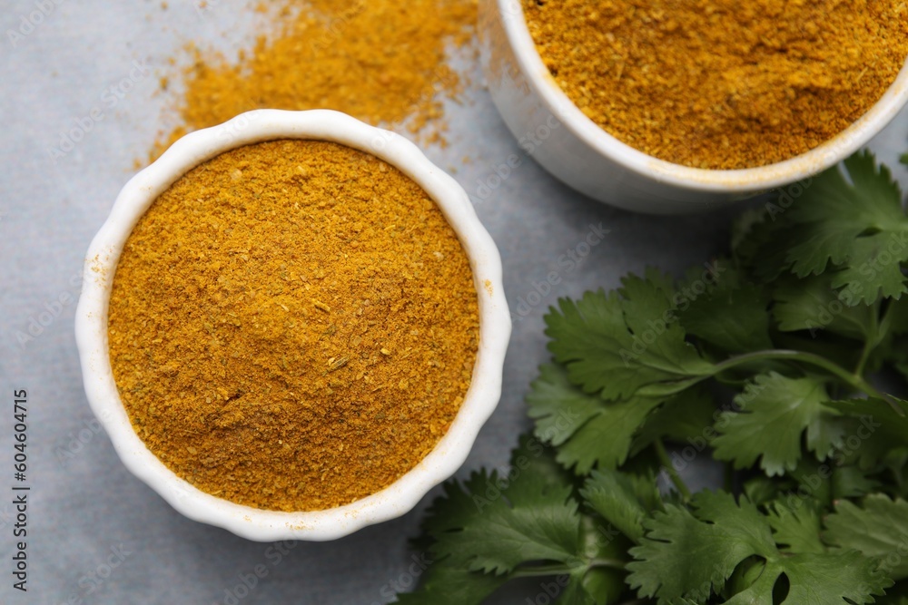Aromatic curry powder and parsley on light grey table, flat lay Aromatic curry powder and parsley on light grey table, flat lay