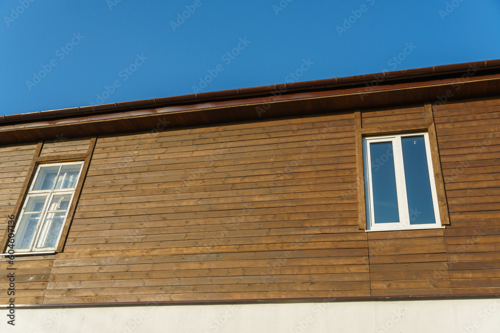 The exterior of a new modern wooden house and double-glazed windows in wooden walls. Design and architecture of private houses. Repair and maintenance of double-glazed windows.