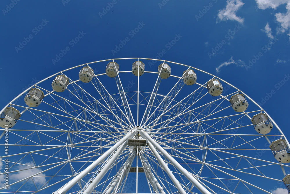 giant ferris wheel detail. white gondolas. steel frame construction. giant spokes in large wheel. leisure and relaxation concept. parks and outdoors. blue sky and white clouds. entertainment and fun giant ferris wheel detail. white gondolas. steel frame construction. giant spokes in large wheel. leisure and relaxation concept. parks and outdoors. blue sky and white clouds. entertainment and fun
