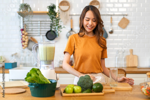 Portrait of beauty healthy asian woman making green vegetables detox cleanse and green fruit smoothie with blender.young girl drinking glass of green fruit smoothie in kitchen.Diet concept.healthy 