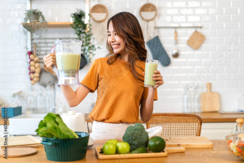 Portrait of beauty healthy asian woman making green vegetables detox cleanse and green fruit smoothie with blender.young girl drinking glass of green fruit smoothie in kitchen.Diet concept.healthy 