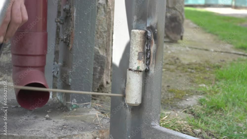 Welding A Gate Hinge,the work of a welder, a man welds hinges for a gate, a welder works Welding A Gate Hinge,the work of a welder, a man welds hinges for a gate, a welder works