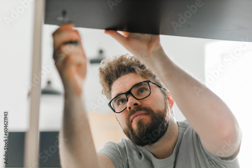 Portrait of man assembling furniture. Do it yourself furniture assembly at home © satura_