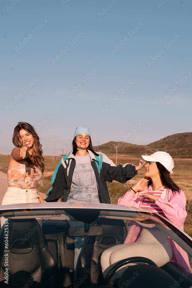 Vertical shot of The three friends travel in a white convertible car during summer vacation.