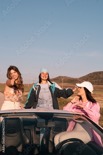 Vertical shot of The three friends travel in a white convertible car during summer vacation. © Alberto Cotilla