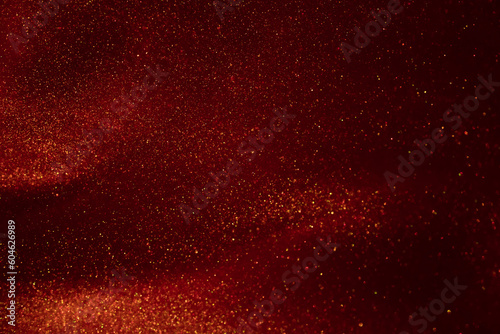 Glittering flows of gold particles in red fluid.