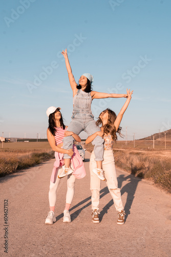girls who travel during the summer lift their companion by the legs and raise their hands in joyfulness