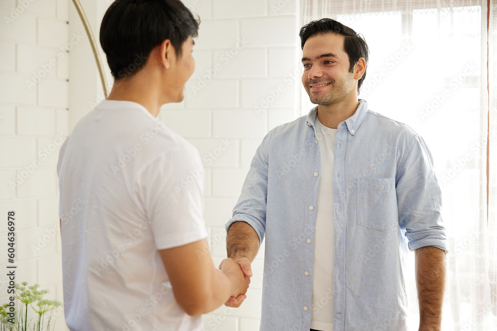 young man shaking hands with his friends in living room young man shaking hands with his friends in living room