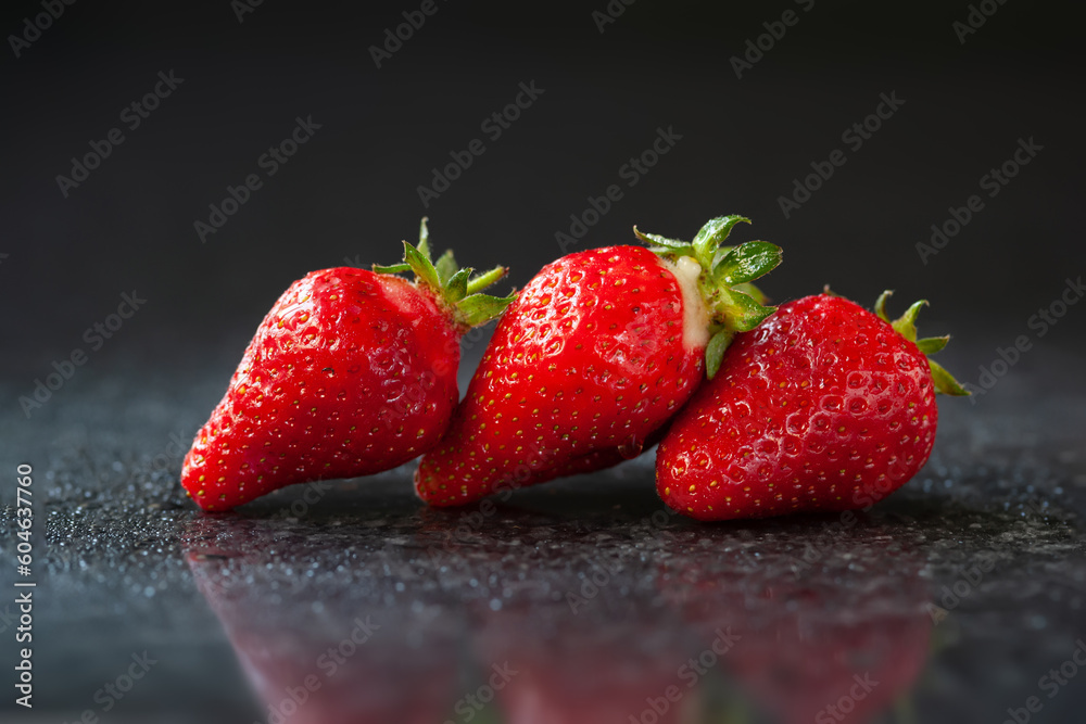 Strawberry. Ripe wet strawberries on a black background with reflection. Brilliant glare. Selective focus Strawberry. Ripe wet strawberries on a black background with reflection. Brilliant glare. Selective focus