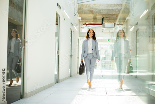 Pretty young business woman walking with briefcase in the office hallway © BGStock72