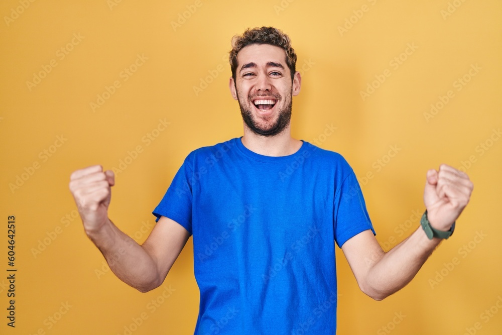 Hispanic man with beard standing over yellow background celebrating surprised and amazed for success with arms raised and eyes closed. winner concept. Hispanic man with beard standing over yellow background celebrating surprised and amazed for success with arms raised and eyes closed. winner concept.