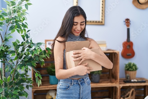 Young hispanic girl smiling confident holding package at home photo