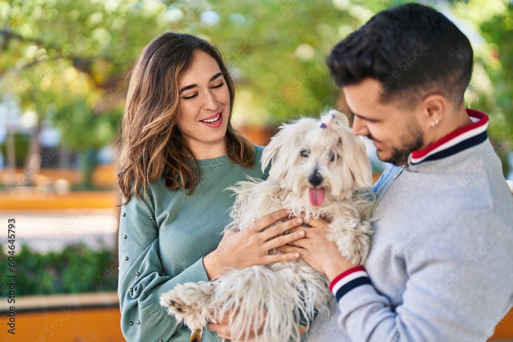 Man and woman holding dog standing together at park Man and woman holding dog standing together at park