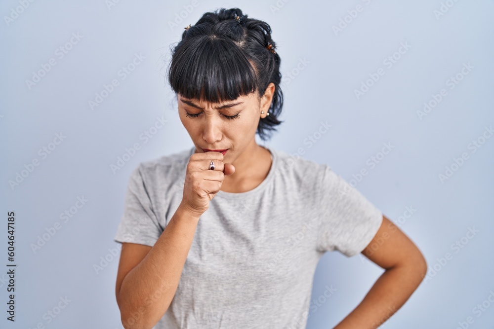 Young hispanic woman wearing casual t shirt over blue background feeling unwell and coughing as symptom for cold or bronchitis. health care concept. Young hispanic woman wearing casual t shirt over blue background feeling unwell and coughing as symptom for cold or bronchitis. health care concept.