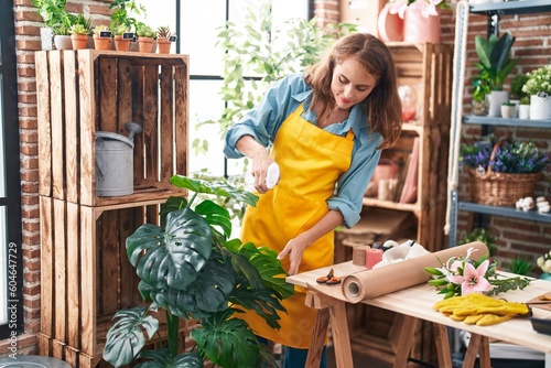 Young beautiful hispanic woman florist using difusser working at florist