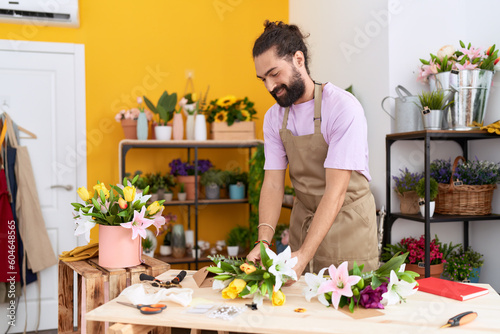 Young hispanic man florist make bouquet of flowers at flower shop
