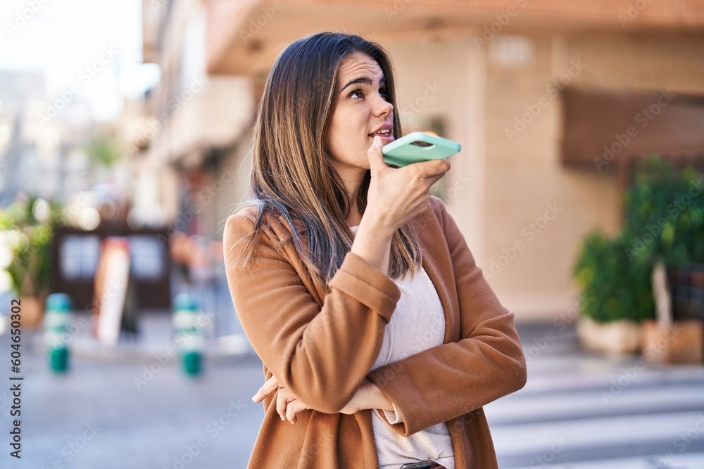 Young beautiful hispanic woman talking on smartphone with serious expression at street