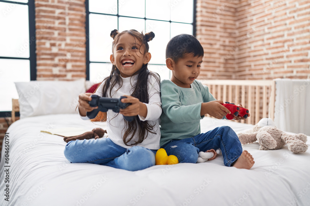 Adorable boy and girl playing video game sitting on sofa at bedroom Adorable boy and girl playing video game sitting on sofa at bedroom