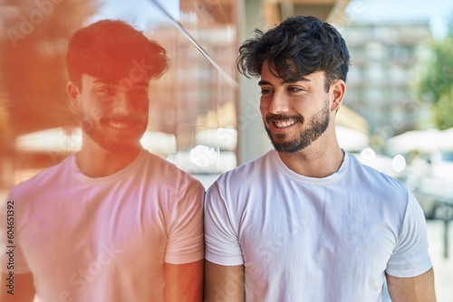 Young hispanic man smiling confident looking to the side at street