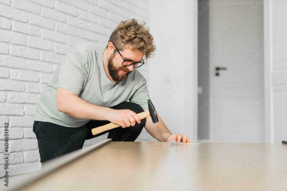 Bearded millennial man assemble his bookcase. He uses tools for furniture. Furniture for the interior room or apartments