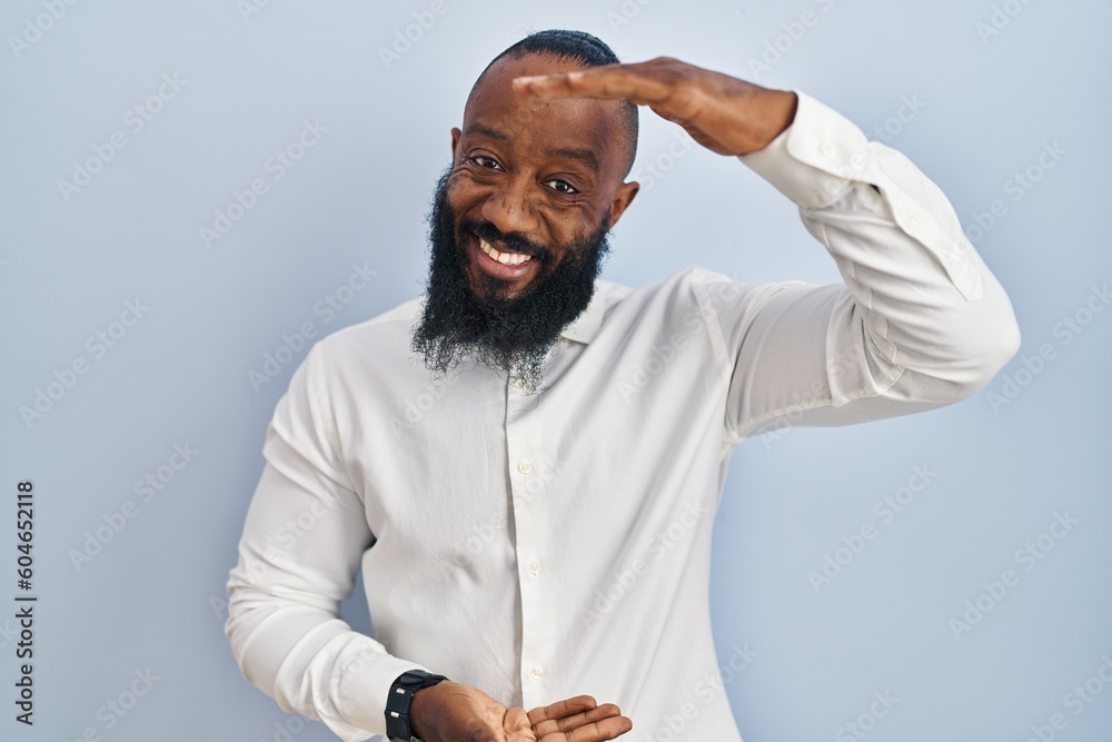 African american man standing over blue background gesturing with hands showing big and large size sign, measure symbol. smiling looking at the camera. measuring concept. African american man standing over blue background gesturing with hands showing big and large size sign, measure symbol. smiling looking at the camera. measuring concept.