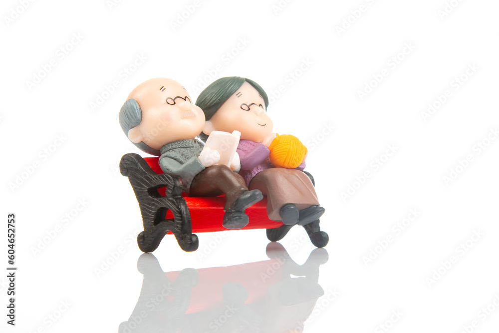 miniature people. figures for the concept. a couple of retired people are sitting together on a bench. old age and helping each other miniature people. figures for the concept. a couple of retired people are sitting together on a bench. old age and helping each other