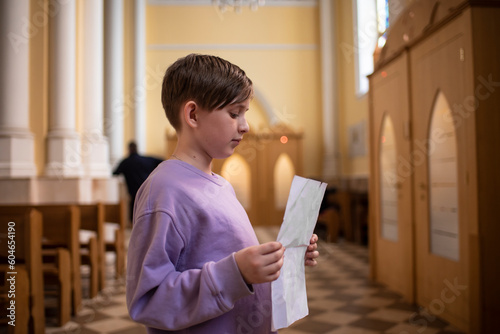 a boy stands in front of a confessional in a Catholic church, preparing for his first confession photo