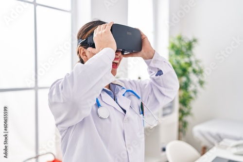 Young beautiful hispanic woman doctor using virtual reality glasses at clinic © Krakenimages.com