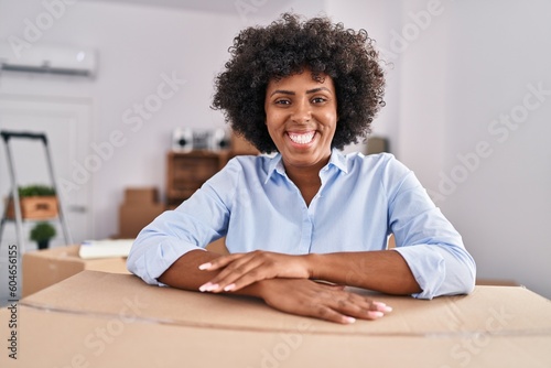 African american woman smiling confident leaning on package at new home