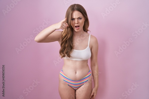 Caucasian woman wearing lingerie over pink background pointing displeased and frustrated to the camera, angry and furious with you © Krakenimages.com