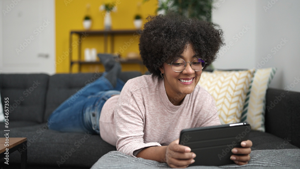 Young african american woman using touchpad lying on sofa at home Young african american woman using touchpad lying on sofa at home