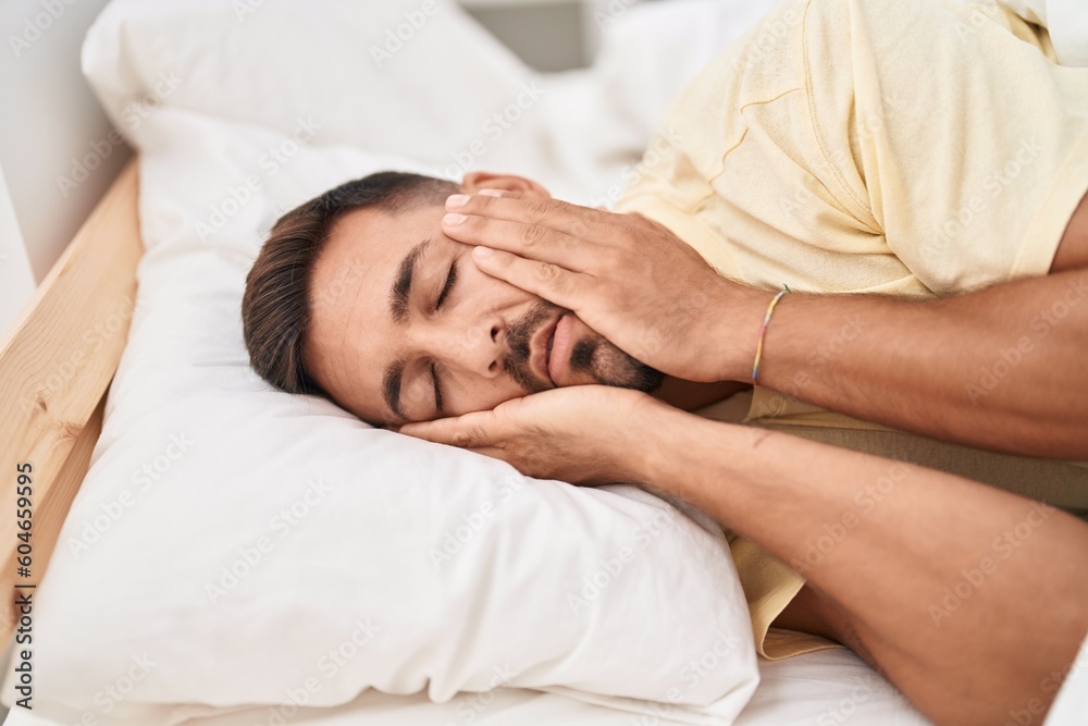 Young hispanic man stressed lying on bed at bedroom