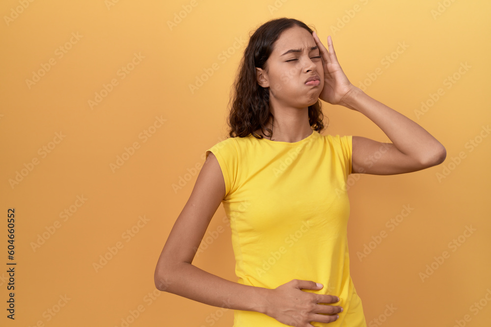 Young african american woman suffering for stomach and head ache standing over isolated yellow background Young african american woman suffering for stomach and head ache standing over isolated yellow background