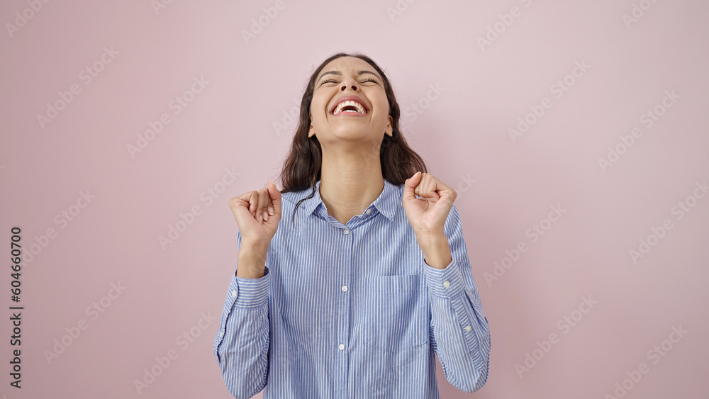 Young beautiful hispanic woman standing with winner expression over isolated pink background Young beautiful hispanic woman standing with winner expression over isolated pink background
