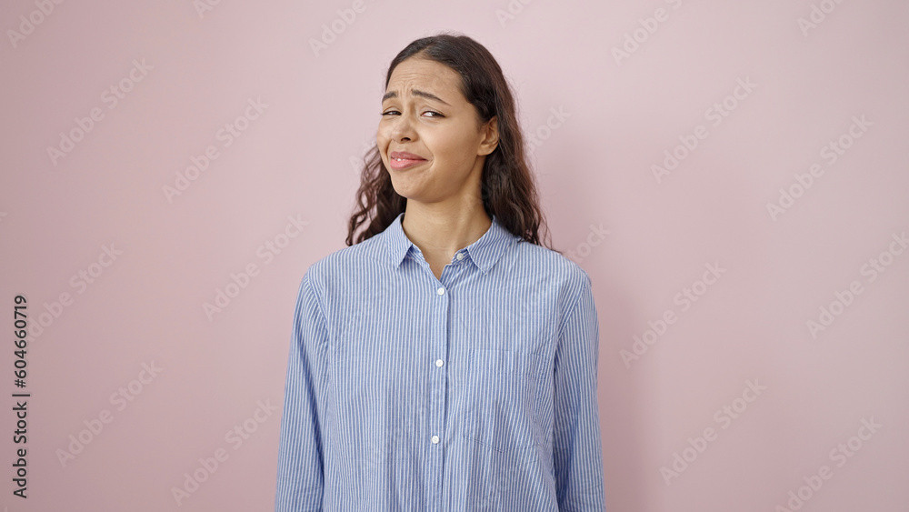 Young beautiful hispanic woman standing with doubt expression over isolated pink background Young beautiful hispanic woman standing with doubt expression over isolated pink background