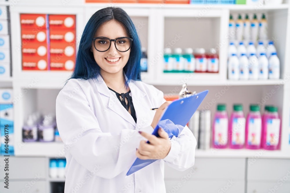 Young caucasian woman pharmacist smiling confident writing on document at pharmacy