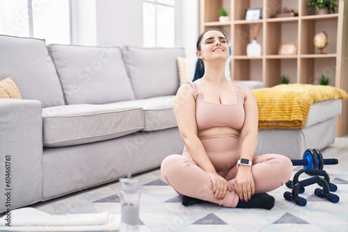 Young caucasian woman stretching head sitting on floor at home