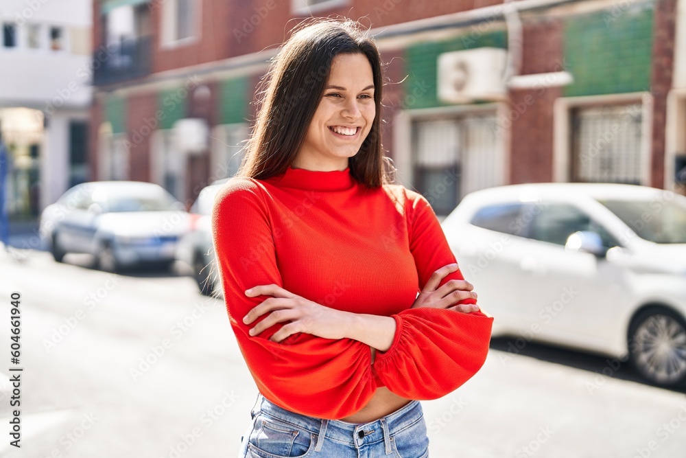 Young beautiful hispanic woman standing with arms crossed gesture at street