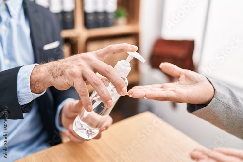 Mother and son business workers wearing medical mask using sanitizer gel hands at office