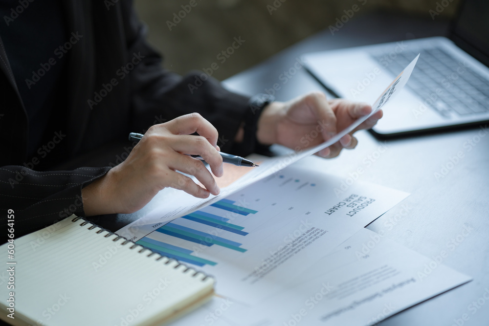 Close-up of Asian Businesswoman working at the home office and analyzing financial report document. Accounting and Finance concept. Close-up of Asian Businesswoman working at the home office and analyzing financial report document. Accounting and Finance concept.