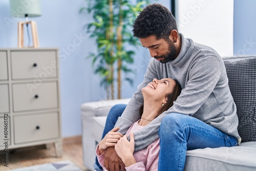 Man and woman couple hugging each other sitting on sofa at home