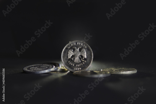 Selective blur on a one ruble coin with the mention one ruble and bank of russia written in russian, isolated on a black background. RUB, or russian ruble, is official currency and money of Russia. © Jerome