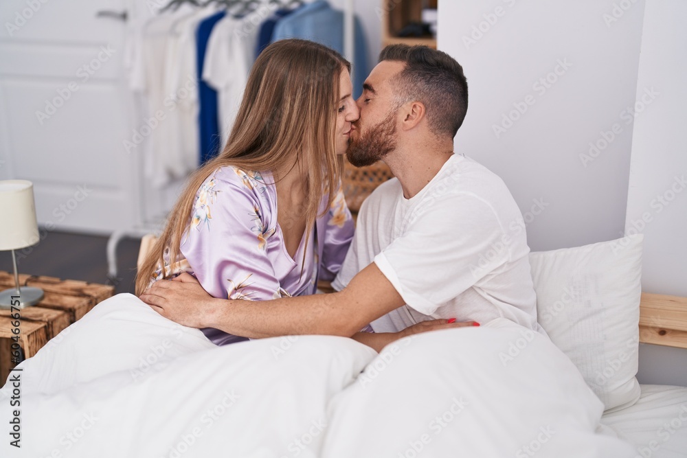 Man and woman couple sitting on bed kissing at bedroom Man and woman couple sitting on bed kissing at bedroom