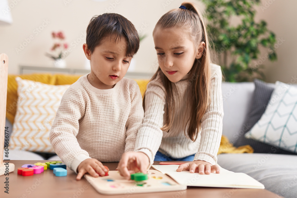 Adorable boy and girl playing with maths puzzle game standing at home Adorable boy and girl playing with maths puzzle game standing at home