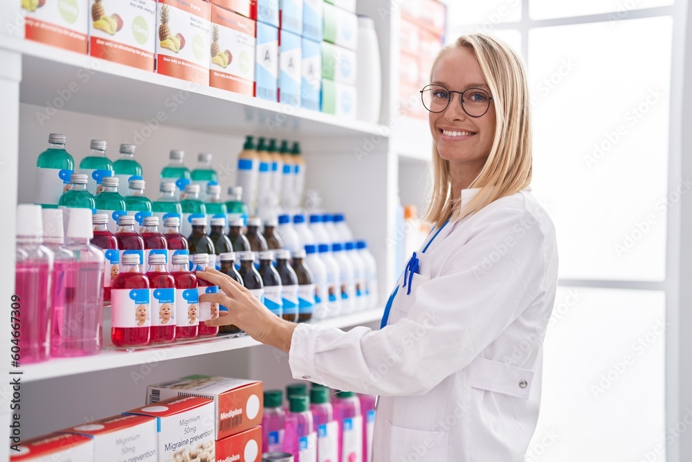 Young blonde woman pharmacist smiling confident working at pharmacy